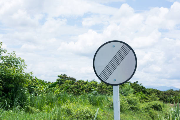 Restriction ends sign beside the road with tree and sky background