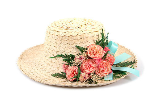 Woven woman hat with artificial rose flowers and leaf with blue ribbon isolated on white background