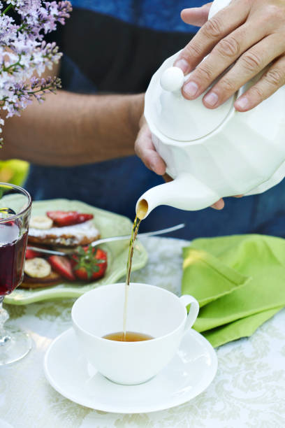 istock A man pours tea into a cup. Summer breakfast in the garden 988550178