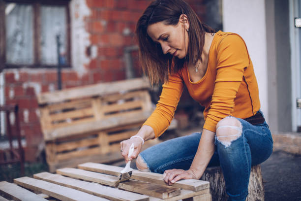 istock Woman carpenter varnishing board 988552708