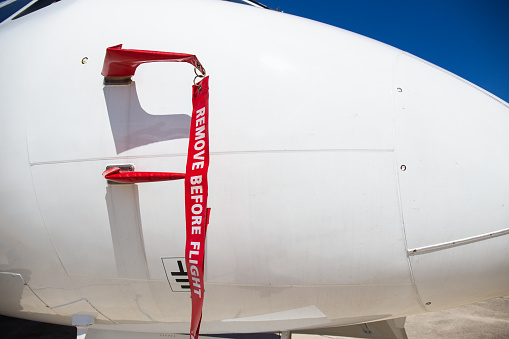 remove before flight flag cover pitot static tube of white aircraft at parking area in airport
