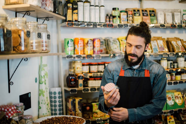 istock Young trader holding a jar product at the store 988586592