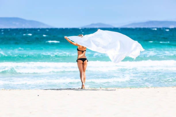 istock Beautiful Woman Holding White Fabric on a Beach 988600674