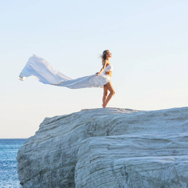 istock Beautiful Woman Posing With Fabric on the Rock 988611390