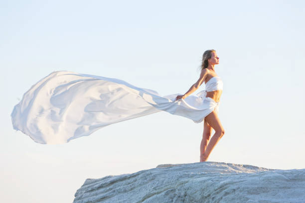 istock Beautiful Woman Posing With Fabric on the Rock 988611532