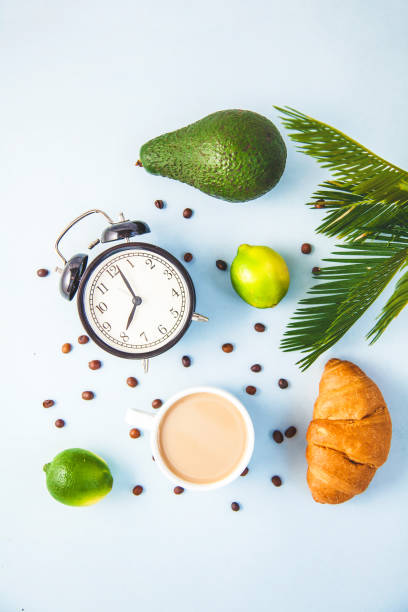 morning coffee in a white cup croissant avocado lime awakening with an alarm clock breakfast cheerfulness, a healthy breakfast freshness copy space top view - wakening imagens e fotografias de stock
