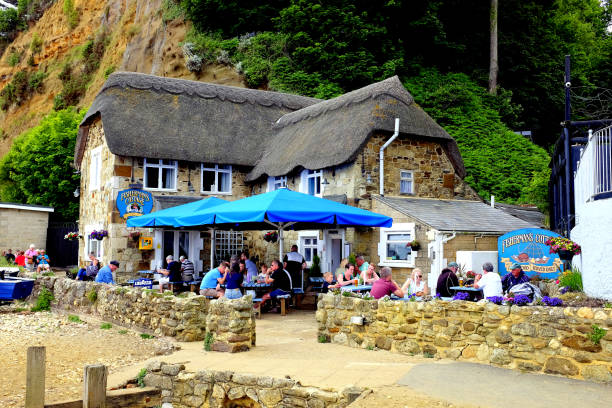 Thatched pub, Shanklin, Isle of Wight, UK. Shanklin, Isle of Wight, UK. June 20, 2018. Holidayamkers and locals enjoying a meal at the thatched Fishermans cottage on the beach at Shanklin on the Isle of Wight, UK. table ledge stock pictures, royalty-free photos & images