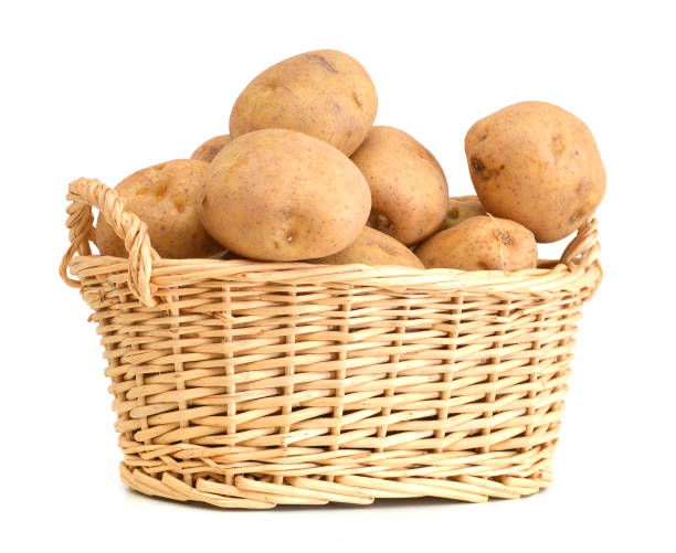 istock Fresh potatoes in basket isolated on white 988644904