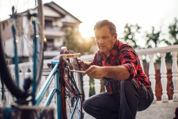 Senior man repairing bicycle in front or back yard