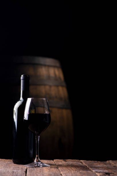 istock A bottle opf red wine and a glass with barrel on background 988656090