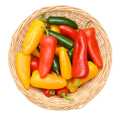 A group of small sweet peppers in basket on a white background.