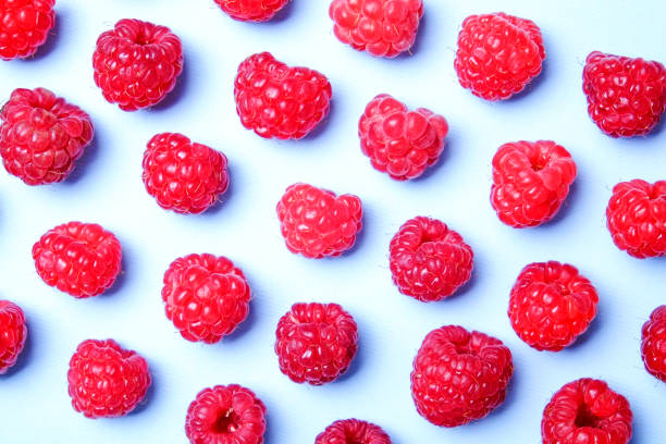 istock Bunch of fresh organic raspberry berries in seamless ornament pattern, white background. Clean eating concept. Healthy nutritious vegan snack, tasty raw diet. Close up, copy space, top view, flat lay. 988665014