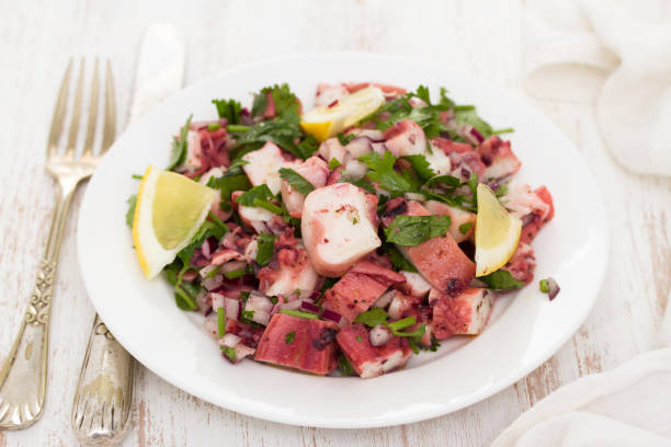 istock octopus salad with lemon on white dish on wooden background 988669486