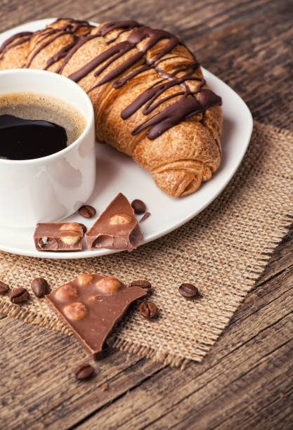 Breakfast with coffee, milk and croissants on wooden table