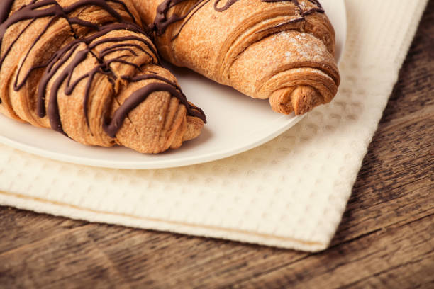 istock Fresh Croissants on wooden rustic background. Soft vintage color 988670870