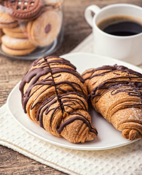 istock Cappuccino and croissant on wooden table 988670888
