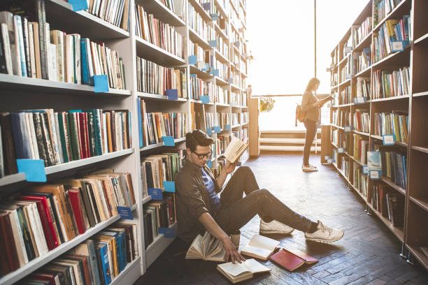 istock Pensive male looking through books 988674384