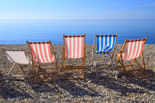 Row of empty deck chairs on the beach in Devon