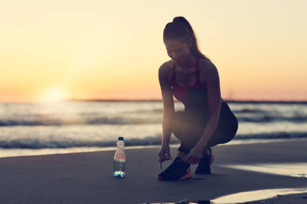 istock Woman running alone at beautiful dusk on the beach 988703880