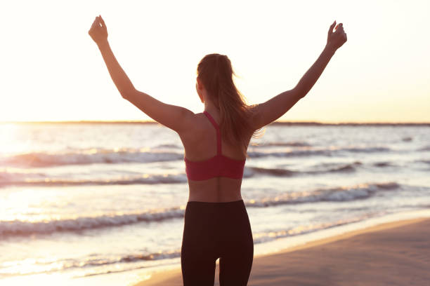 istock Woman running alone at beautiful dusk on the beach 988707838