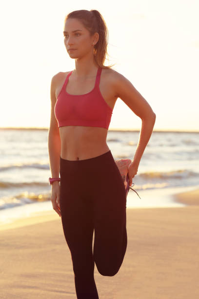 istock Woman running alone at beautiful dusk on the beach 988714318
