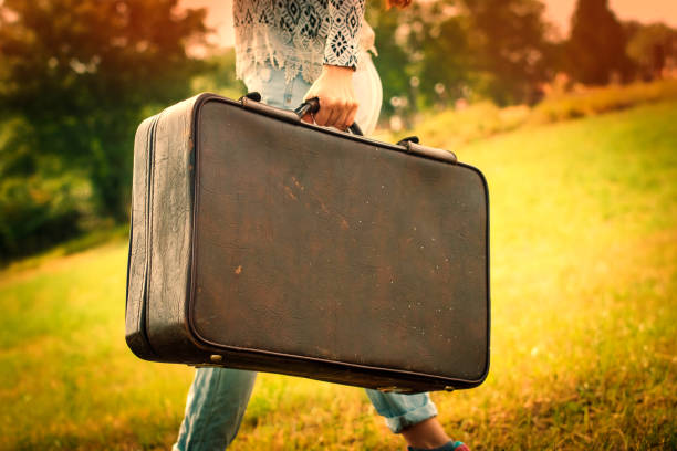 istock Pretty young woman in a field with a old suitcase 988715822