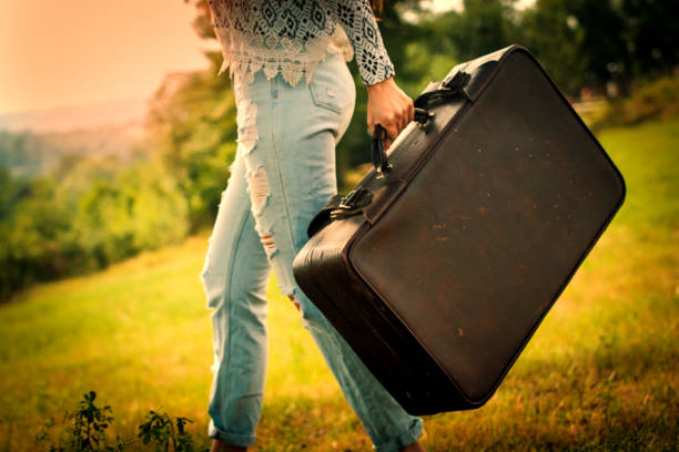 istock Pretty young woman in a field with a old suitcase 988719902