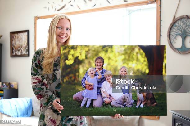 Happy Young Woman Holding Canvas Print Of Family Portrait Stock Photo - Download Image Now
