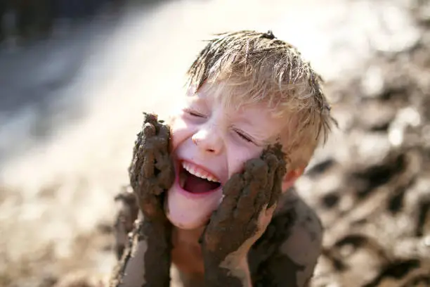 Photo of Cute Little Boy Playing Outside in the Mud with a Dirty Face