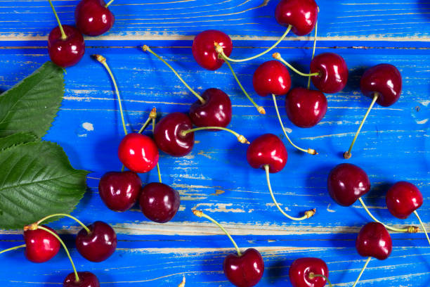 istock Cherries on blue wooden desk 988752140