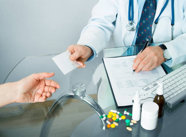 istock doctor at his workplace give a recipe to patient and write 988765320