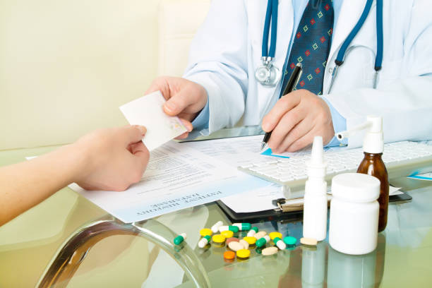 istock doctor at his workplace give a recipe to patient and write 988765338