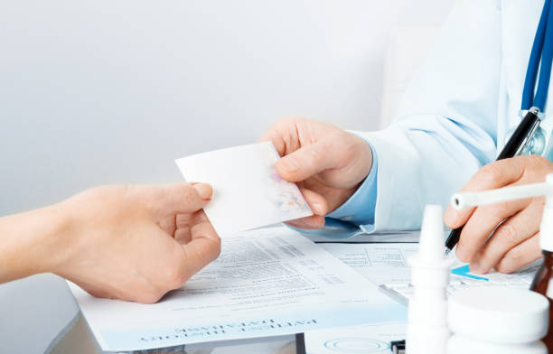 istock doctor at his workplace give a recipe to patient and write 988765364