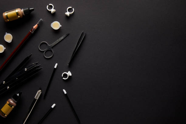 elevated view of scissors, pencil and brushes for permanent makeup isolated on black