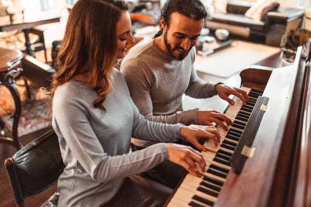 coppia che suona il pianoforte in un appartamento di lusso - piano men pianist musician foto e immagini stock