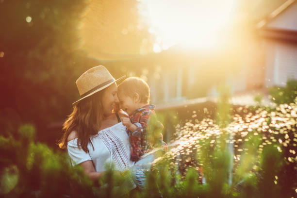 Family in the garden in sunset Mother and her little sun watering plants in garden in summer residential garden stock pictures, royalty-free photos & images