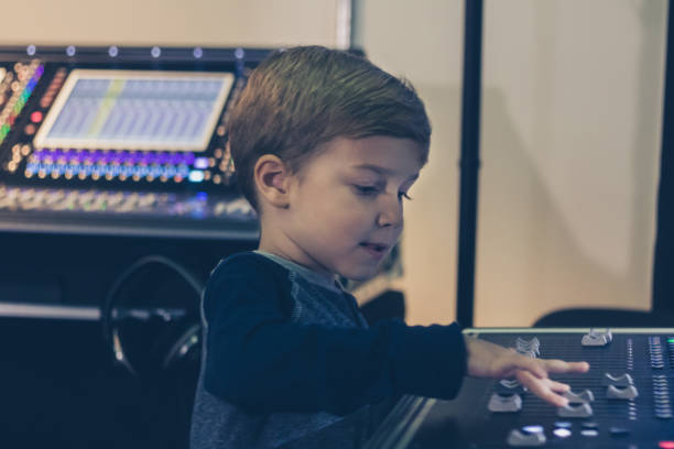 istock Little DJ adjusting sound on audio mixer in music studio. 988876666