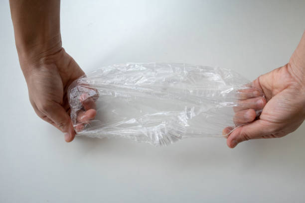 istock Hand expanding disposable shower cap against white background in hotel bathroom. 988925624
