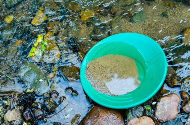 Gold pan filled with mineral rich material ready to pan in stream. Fun and adventure of panning for gold and gemstones. Recreational outdoor activity of prospecting for gold and gems.