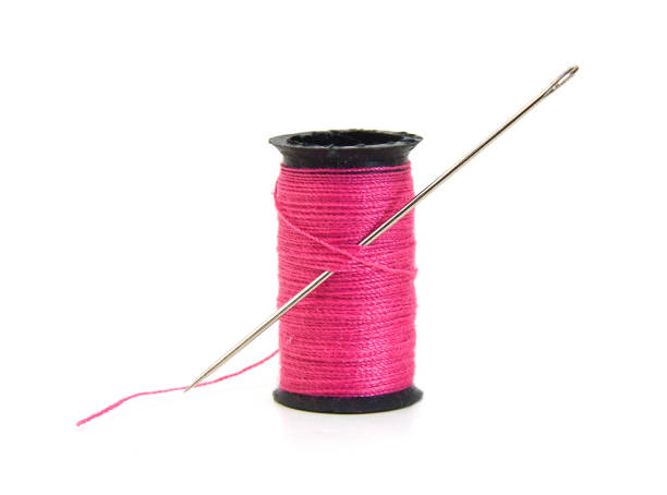 istock Spool of pink thread and needle isolated on white background 988954316