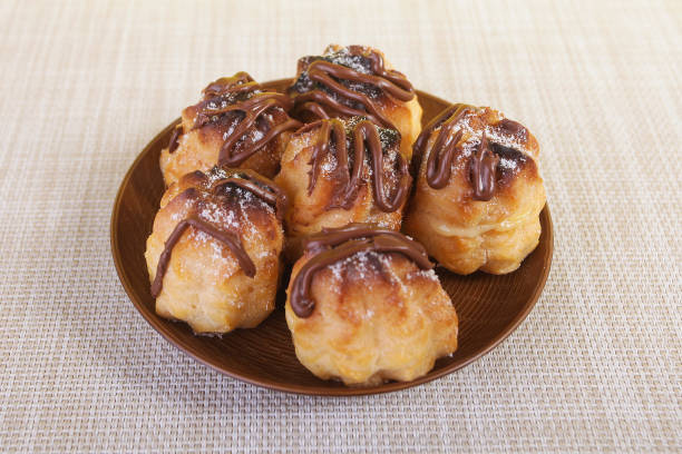 istock Chocolate cream puff on wooden background. 988969946