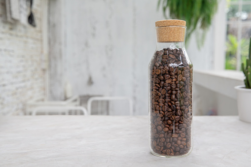 Coffee beans in glass bottles in a clear coffee cafe.