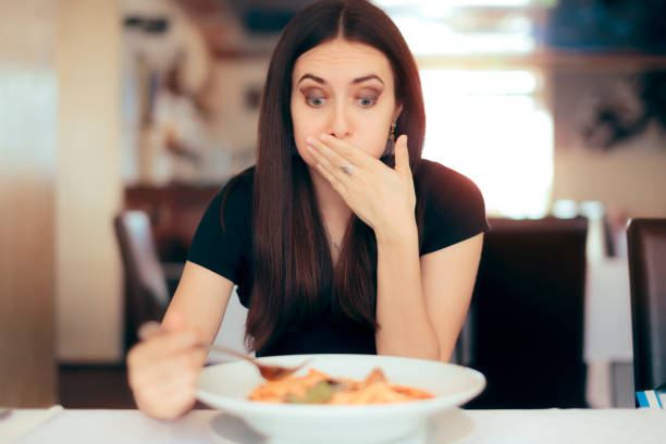 woman feeling sick while eating bad food in a restaurant - stomachache illness pain indigestion imagens e fotografias de stock