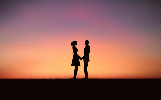 istock Silhouette couple holding hand and standing together on hill under sunset sky background 989013542