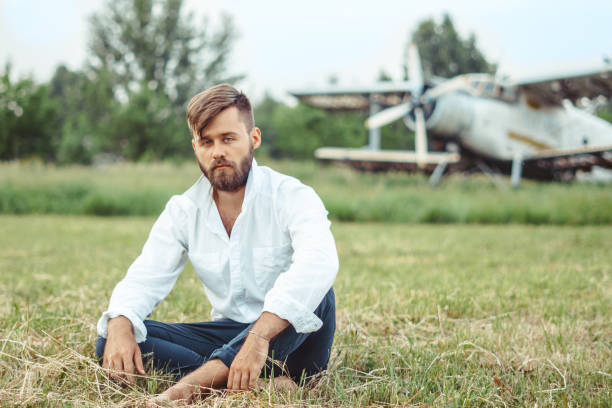 古い飛行機で草の上に座っている男 - airplane seat ストックフォトと画像