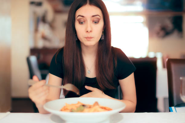 woman feeling sick while eating bad food in a restaurant - full contact imagens e fotografias de stock