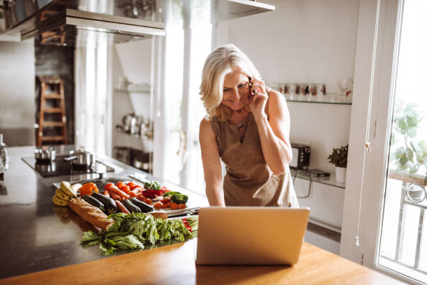 istock woman using laptop and make a phone call in the kitchen 989095284