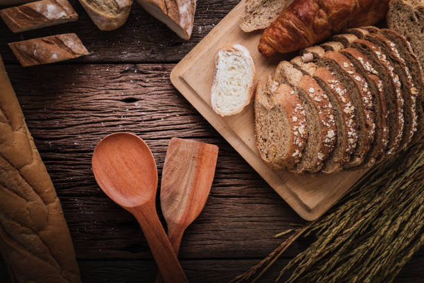 istock Fresh baked bread on dark wood table with copy space background  still life composition with wheat flour spread around with rice wheat. 989108472