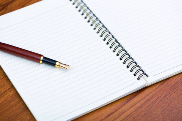 istock Fountain pen or ink pen with notebook paper on wooden working table with copy space, office desk concept. 989108556