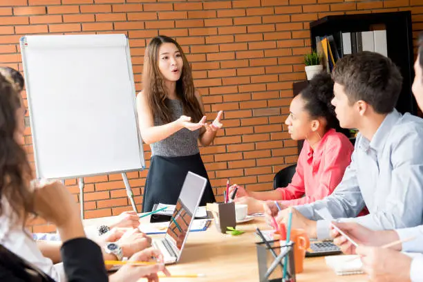 Photo of Asian female leader presenting work the in meeting